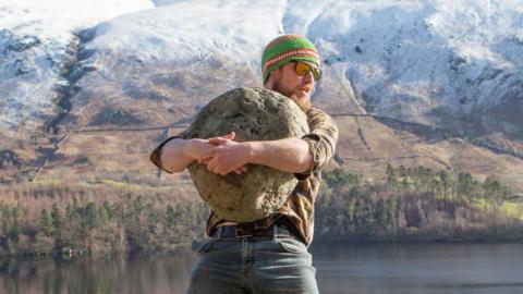 Calum Stott lifting a granite-looking ancient stone