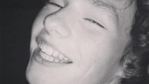 A black and white photo of a smiling Gabriel Santer, who has curly hair.
