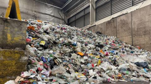 A heap of loose rubbish is piled up in the corner of a warehouse