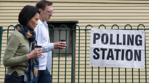 Two people walk past a polling station