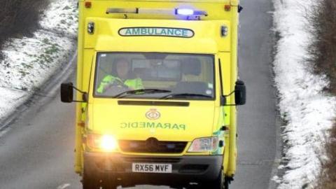 An ambulance drives on a snowy road  