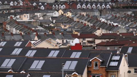 A view of the roofs and houses from a high vantage point. Most are terraced houses. 