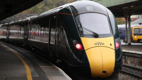 A yellow and green train with the GWR logo on the front pulls in to Bristol Temple Meads. 