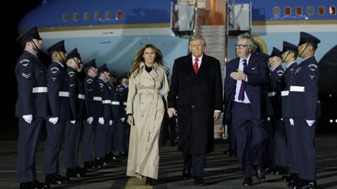US first lady Melania Trump and President Donald Trump walk past honour guards after disembarking from Air Force One