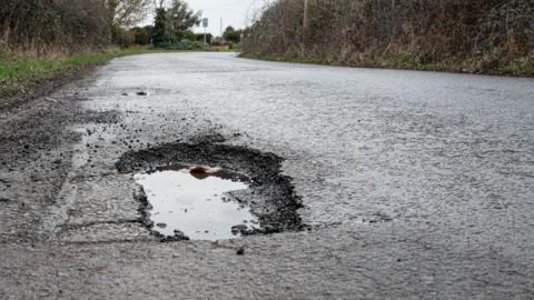 A pothole filled with water on a rural road