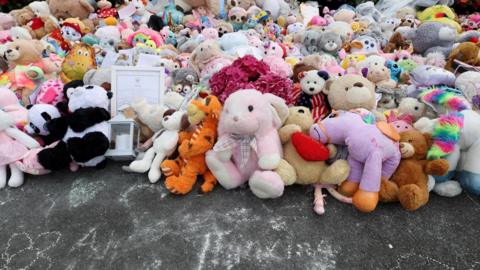 A huge pile of different cuddly toys on the pavement in Southport