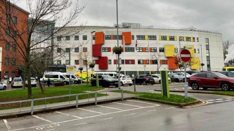 The exterior of Pinderfields Hospital. It is grey with orange and yellow panels.
