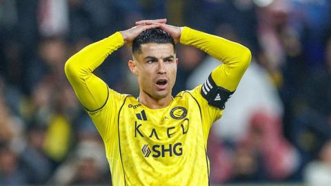 Close-up photograph of Cristiano Ronaldo, playing for Al-Nassr. He has his hands on his head and is wearing the captain's armband