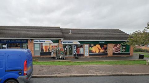 Google Street View of Morrisons Daily store in Pines Road, Exmouth. It is a cloudy day and a blue van is on the left-hand side of the photo.