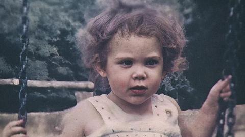 Katrice on a swing, wearing a white dress. Half of her hair is up.