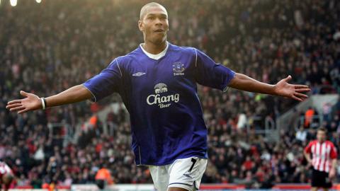 Marcus Bent playing in a blue Everton shirt celebrating with his arms outstretched 