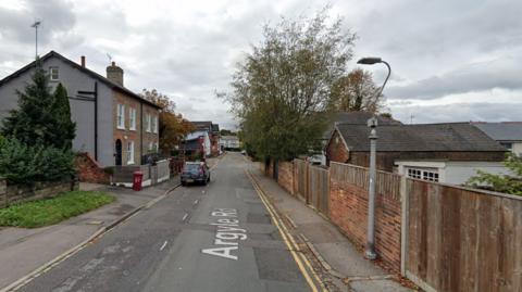 A quiet street with houses on on side and fences on the other