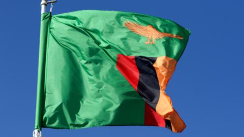 A Zambian flag flutters on a flagpole