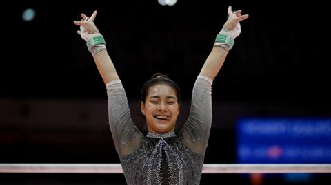 South Korea's Yunseo Lee reacts during her uneven bars exercise 