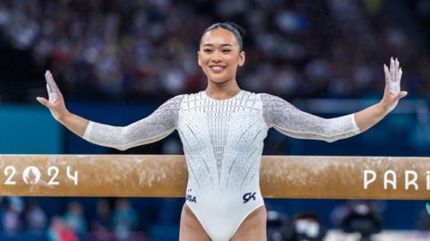 Suni Lee poses with her arms outstretched after competing on the beam at the Paris Olympics