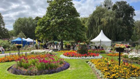 A colourful array of flowerbeds in Vivary Park on a sunny day. There are also tents and marquees set up for the event