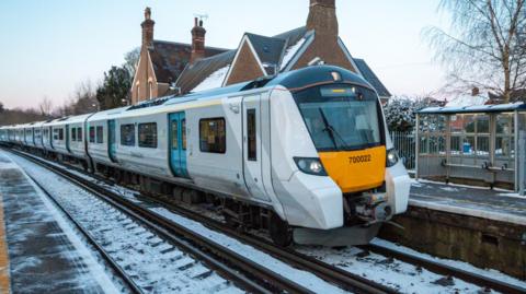 A Thameslink Train at Eynsford Station, with the train driver visible. There is a light dusting of snow on the tracks.