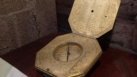An ornate octagonal brass compass/portable sundial.