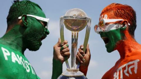 Cricket fans, Arun Haryani (Right) and Anil Advani (Left) pose for a photograph with a replica trophy after painting their bodies in the Indian and Pakistani national flag colours, ahead of the match between India and Pakistan in the ICC World Cup, in Ahmedabad, India, October 11, 2023.