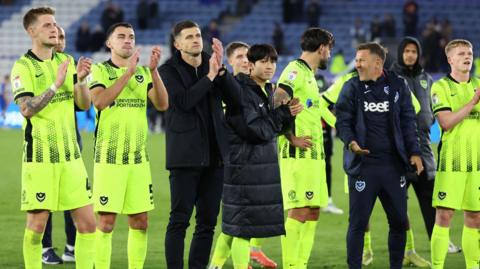 Portsmouth players and staff clap the travelling support at the King Power Stadium