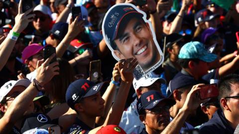 Fans hold up a cardboard cut-out of Sergio Perez 