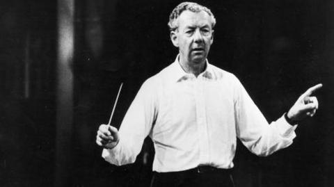 Composer Benjamin Britten conducting while wearing a light-coloured shirt