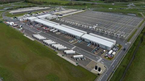 Aerial shot of a a large complex makde up of hangers and lorry parking spaces with lots of lorries in shot