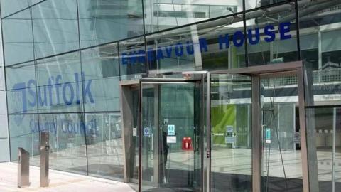 The front of Endeavour House in Ipswich, glass windows and revolving doors with the words Suffolk County Council 