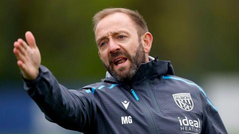Matt Gill points and shots instructions to the players during a training exercise at West Bromwich Albion