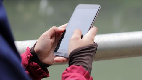 Muslim Girl wearing religious dress and hijab using mobile phone at public park outdoor