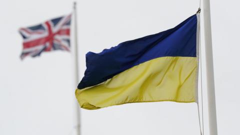 Two flags flying representing Ukraine and the United Kingdom