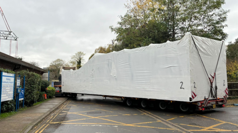 One of the pods arriving at the hospital on the back of a lorry being covered by a big white sheet