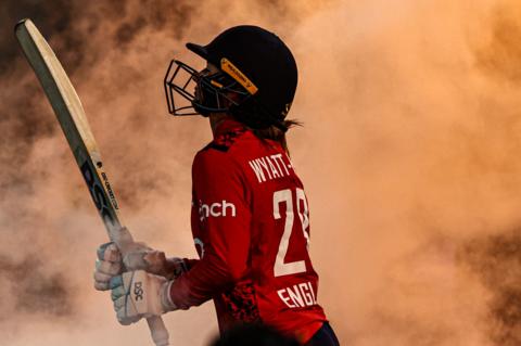 Danni Wyatt-Hodge of England walks out to bat during game one of the Women's Ashes T20 International series between Australia and England at Sydney Cricket Ground in Sydney, Australia, with smoke in the background