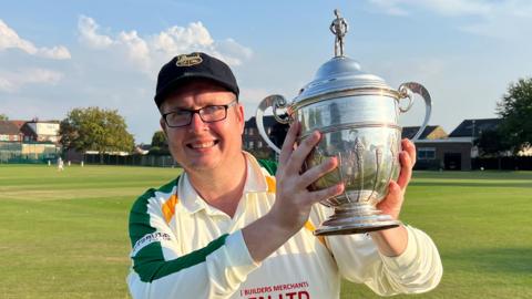 Brian Devine holding a trophy from the Bradford Cricket League in 2023
