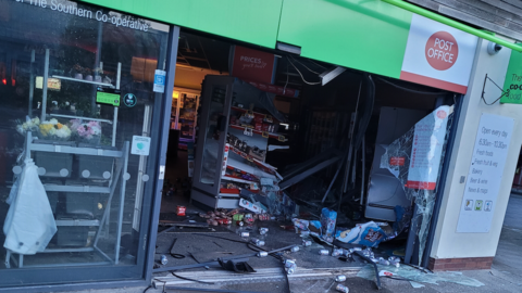 A Co-op shop window and door is smashed and debris is on the ground after a ram raid.