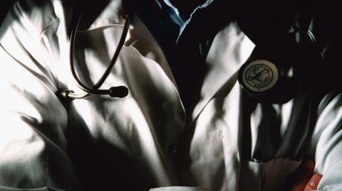 Close up of man's torso, wearing a white lab coat and stethoscope 