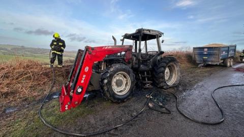 Firefighter dealing with a tractor fire in Petton Cross, near Shillingford, in Devon