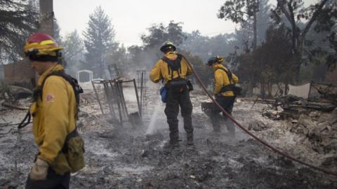 Firefighters hose down a house burned to the ground in Middletown, California on 15 September 2015.