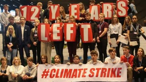 Demonstrators hold a slogan at UN climate talks in Katowice, Poland