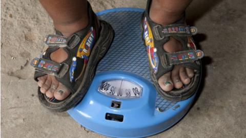 An six-year-old Indian child measures his weight