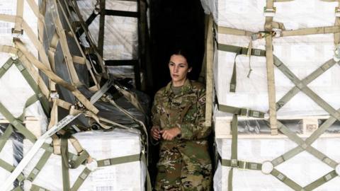 An airman in the cargo bay of a plane carrying baby formula