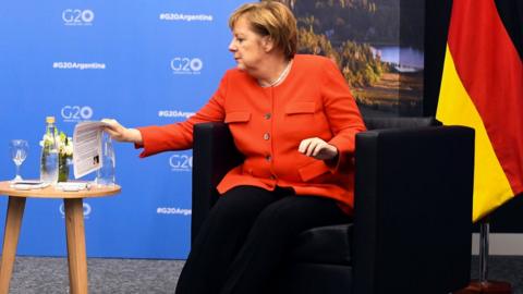 Angela Merkel reaches for a briefing note about Scott Morrison