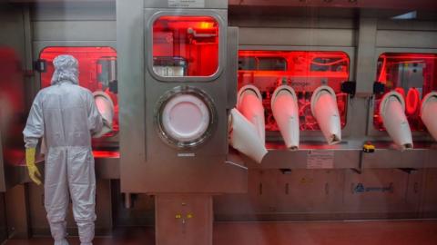 An employee in protective gear works on an assembly line for manufacturing vials of Covishield, AstraZeneca-Oxford's Covid-19 coronavirus vaccine at India's Serum Institute in Pune