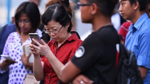 China's consul-general checks her phone at a jetty in Kota Kinabalu after a tourist boat carrying 28 Chinese nationals was reported missing on January 28.