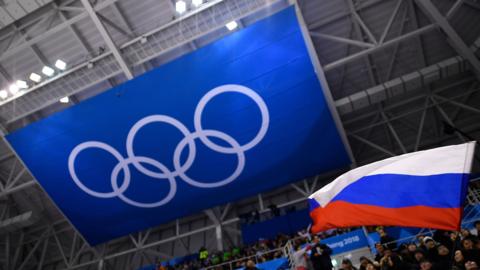 A fan waves the Russian flag beneath a banner of the Olympic rings at the 2018 Winter Olympics in South Korea