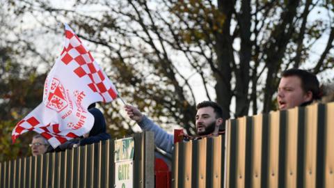Brackley Town fans watch over the fence