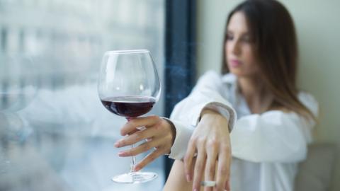 Woman drinking red wine and smoking