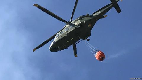 Helicopter dropping water over fire