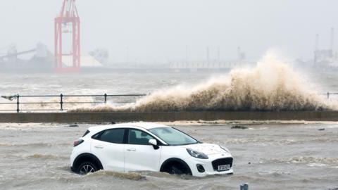 Floodwater rises up around a parked car in New Brighton, Wallasey, on Tuesday.