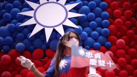A woman poses for photos in front of a Taiwanese flag made with balloons during a fair to mark the National Day at Zhongzhen New Village Cultural Park on October 10, 2023
